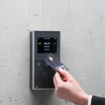 A businessman uses a secure card reader access system against a concrete wall.