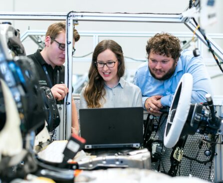 Engineers collaborating on a car project in a modern automotive workshop using advanced technology.
