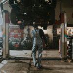 Automobile mechanic fixing a car in a repair garage, focus on service and repair work