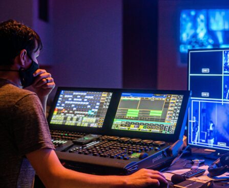 Back view of man in face mask adjusting audio and video on modern equipment during music performance