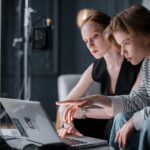 Two focused individuals collaborating on a laptop in a professional indoor setting.