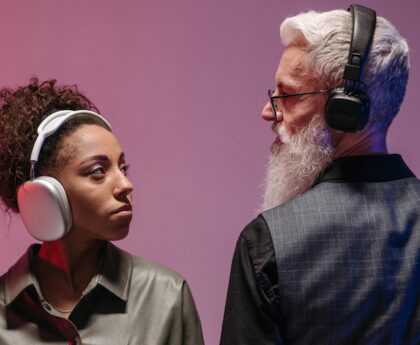 An African American woman and a Caucasian man wearing headphones, enjoying music together indoors.