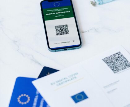 A smartphone displaying a digital vaccine passport alongside Covid-19 documents on a table.