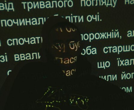 Silhouette of a person with text projected on face against dark background.