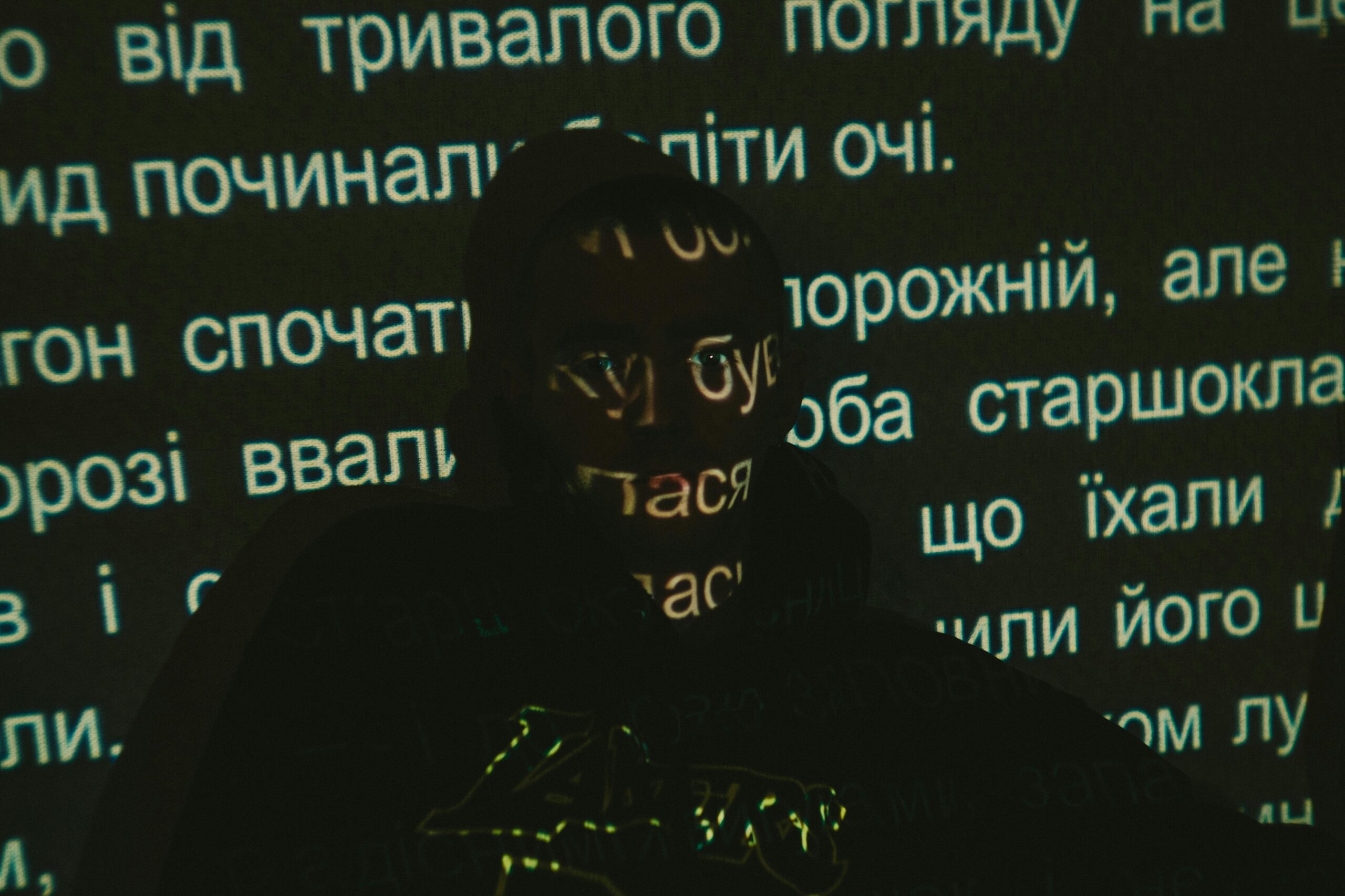 Silhouette of a person with text projected on face against dark background.