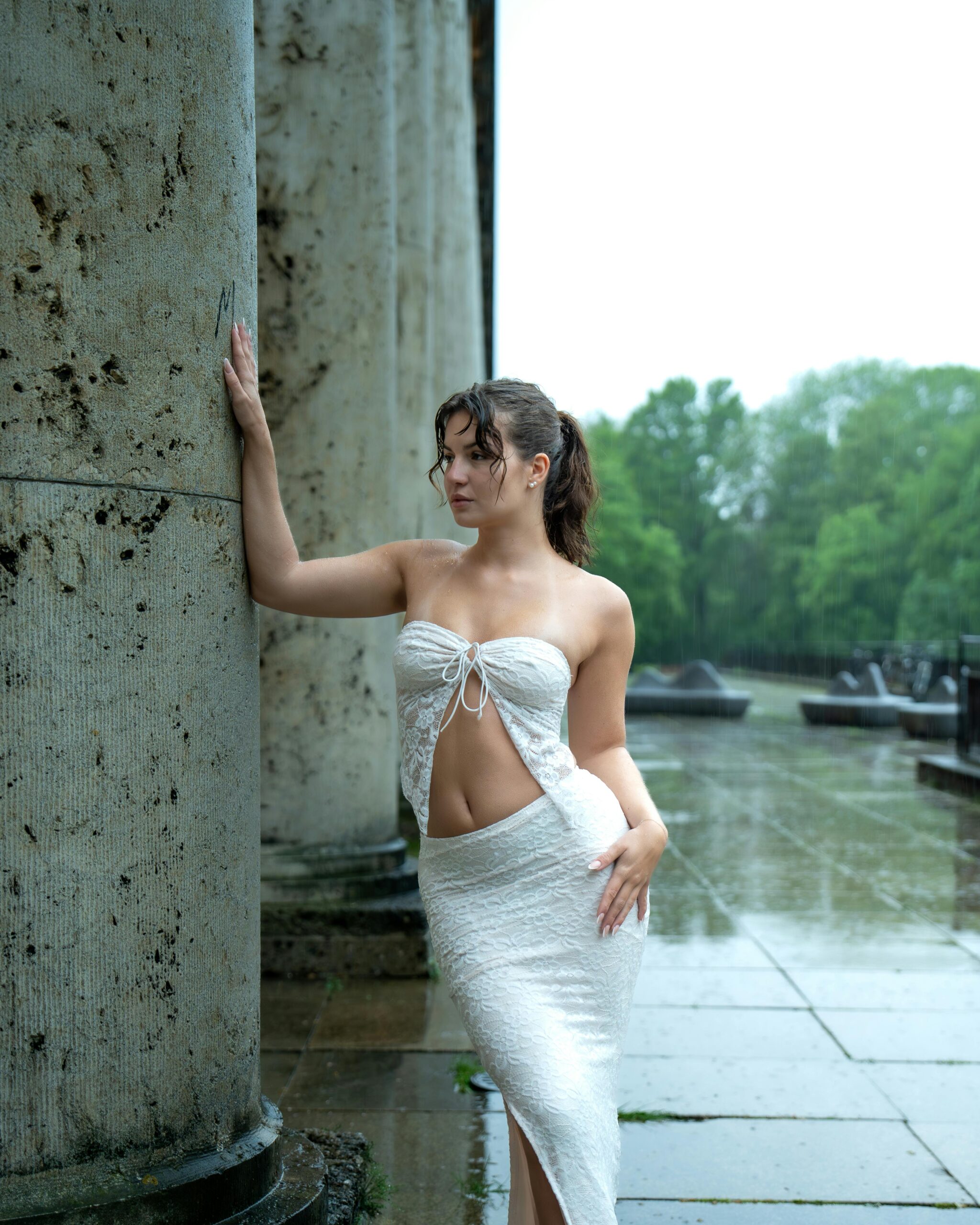 Woman in white dress during an artistic photoshoot in rainy Germany.