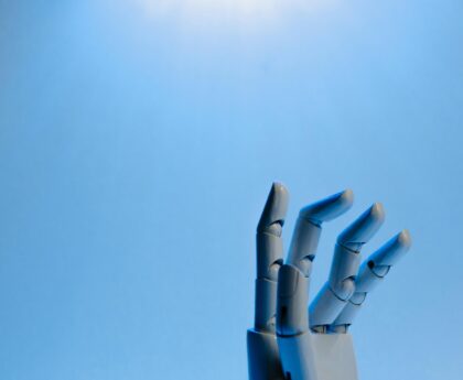 Robotic hand with articulated fingers reaching towards the sky on a blue background.