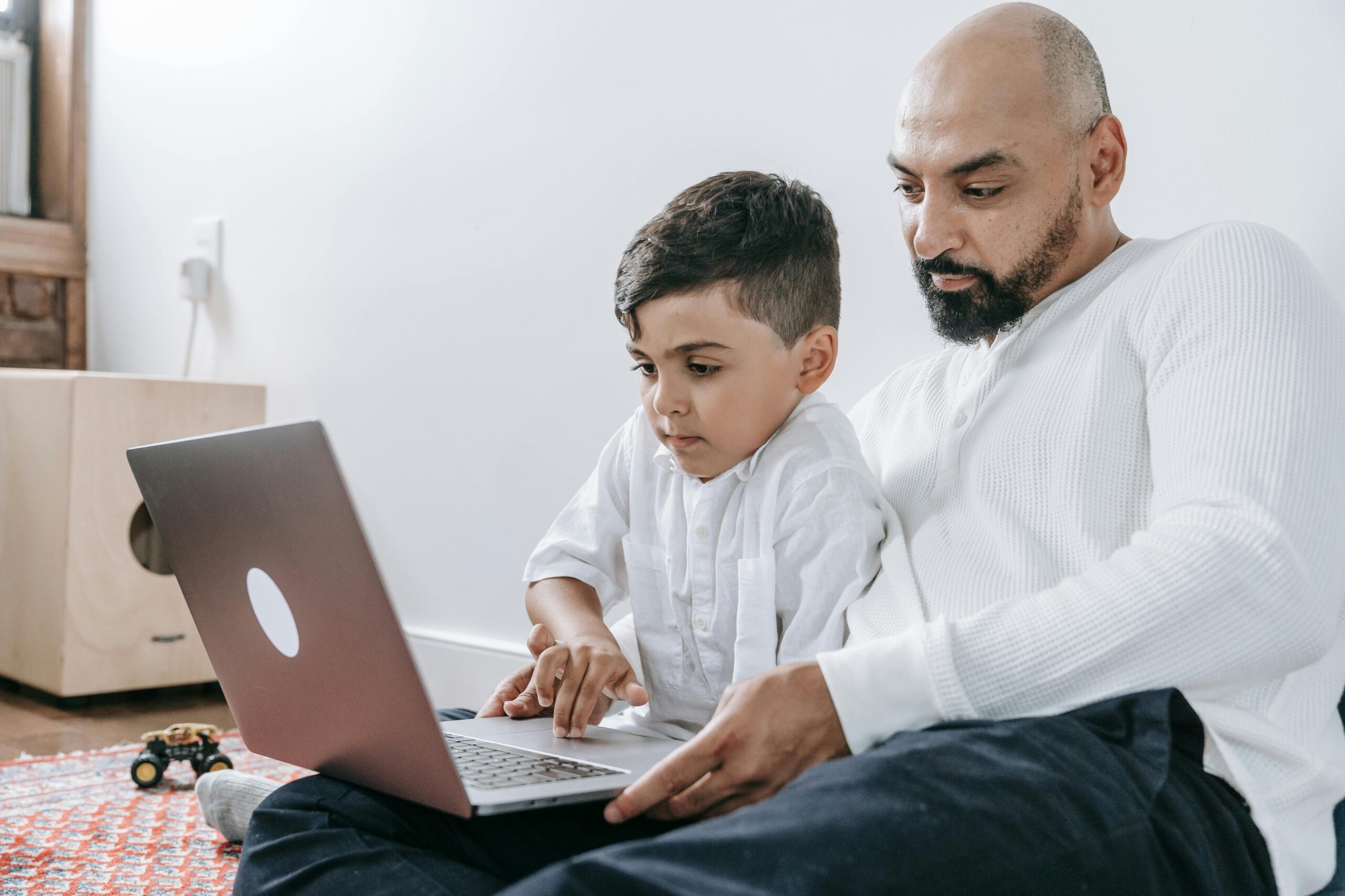A father and son spending quality time together using a laptop, bonding in a cozy indoor setting.